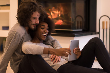 Image showing multiethnic couple used tablet computer on the floor