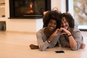 Image showing multiethnic couple used tablet computer on the floor