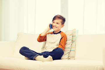 Image showing happy boy calling on smartphone at home