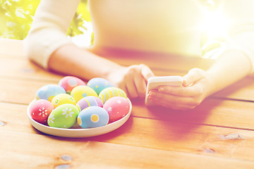 Image showing close up of hands with easter eggs and smartphone