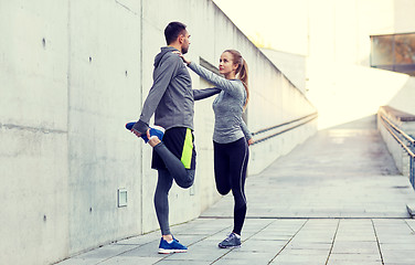 Image showing smiling couple stretching leg outdoors