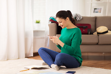 Image showing woman with smartphone and travel map at home