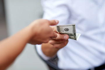 Image showing close up of hands giving and receiving dollar money