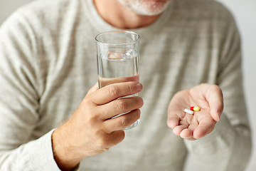 Image showing close up of hands with medicine pills and water