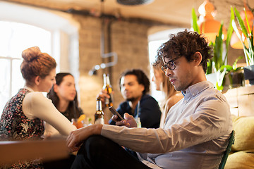 Image showing man with smartphone and friends at restaurant