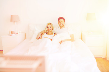 Image showing happy couple lying in bed at home and watching tv