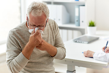 Image showing senior man blowing nose with napkin at hospital