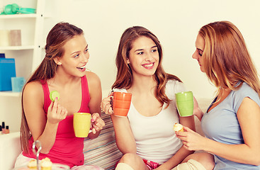 Image showing happy young women drinking tea with sweets at home
