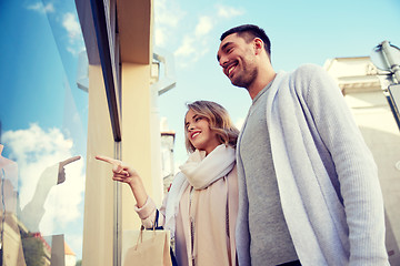 Image showing happy couple with shopping bags at shop window