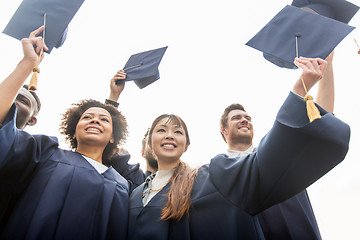 Image showing happy students or bachelors waving mortar boards