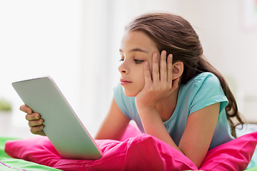 Image showing bored girl with tablet pc lying in bed at home