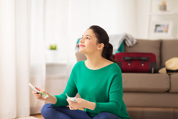 Image showing happy woman with money and travel bag at home