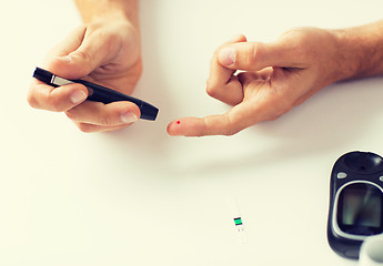 Image showing close up of man checking blood sugar by glucometer