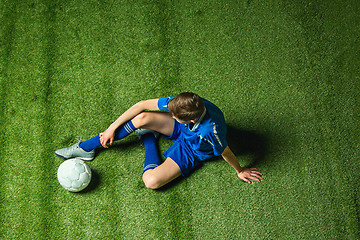 Image showing Boy soccer player sitting on greeb grass