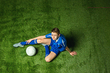 Image showing Boy soccer player sitting on greeb grass