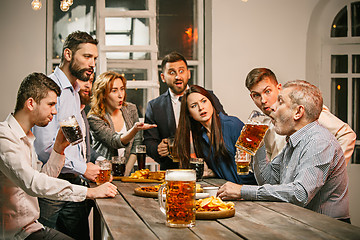 Image showing Group of friends enjoying evening drinks with beer