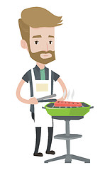 Image showing Young man cooking meat on the barbecue grill.