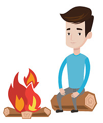 Image showing Man sitting on log near campfire.