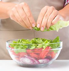 Image showing Cook is tearing lettuce while making salad