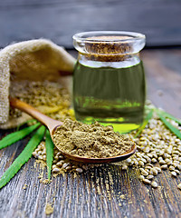 Image showing Flour hemp in spoon with oil and bag on dark board