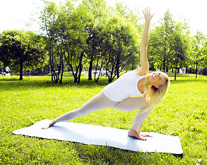 Image showing young pretty blond girl doing yoga in green sunny park at morning, lifestyle sport people concept