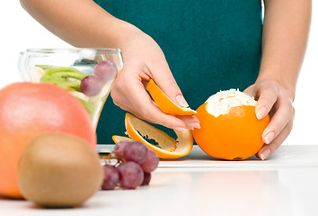 Image showing Cook is peeling orange for fruit dessert