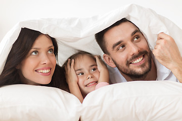 Image showing happy family lying in bed under blanket at home