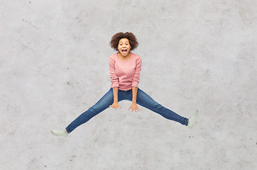 Image showing happy african american woman jumping over white