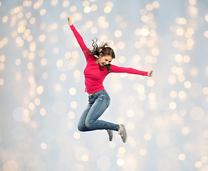 Image showing smiling young woman jumping over holidays lights