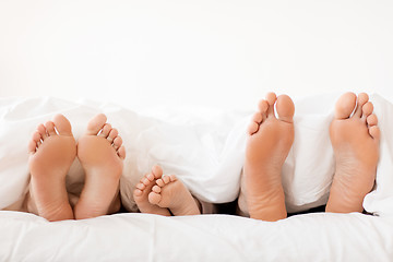 Image showing bare soles of happy family feet in bed at home