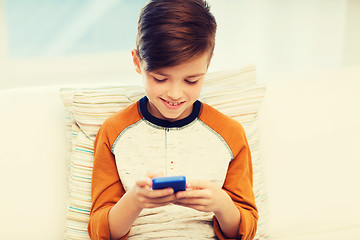 Image showing boy with smartphone texting or playing at home