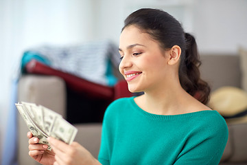 Image showing happy woman with money planning her travel at home