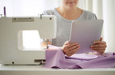 Image showing tailor with sewing machine, tablet pc and fabric