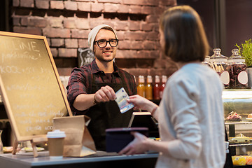 Image showing happy barman and woman paying money at cafe