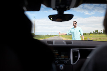 Image showing man hitchhiking and stopping car with thumbs up