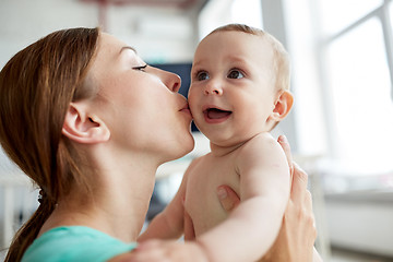 Image showing happy young mother kissing little baby at home