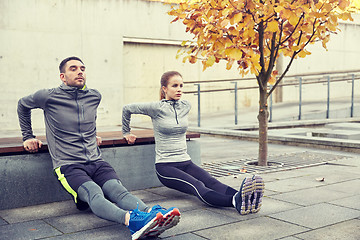 Image showing couple doing triceps dip on city street bench