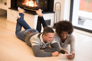 Image showing multiethnic couple used tablet computer on the floor