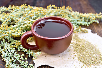 Image showing Tea with wormwood in brown cup on board