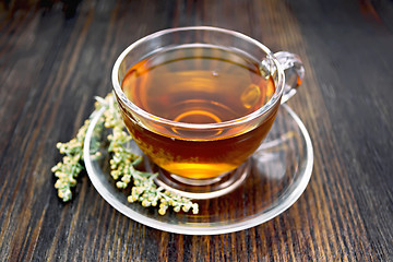 Image showing Tea with gray wormwood in glass cup on board