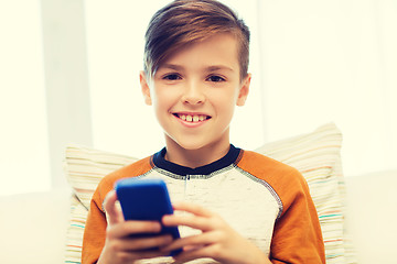 Image showing boy with smartphone texting or playing at home