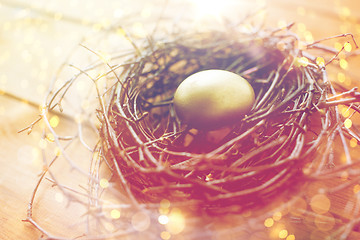 Image showing close up of golden easter egg in nest on wood