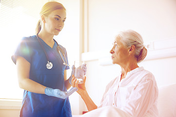 Image showing nurse giving medicine to senior woman at hospital