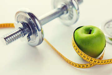 Image showing close up of dumbbell and apple with measuring tape