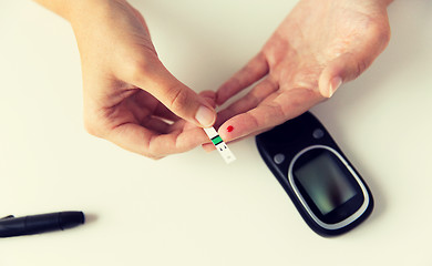 Image showing close up of woman making blood test by glucometer