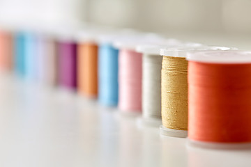 Image showing row of colorful thread spools on table