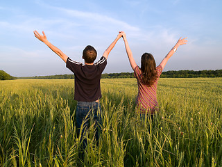 Image showing Young Couple in Field Holding Hands Up