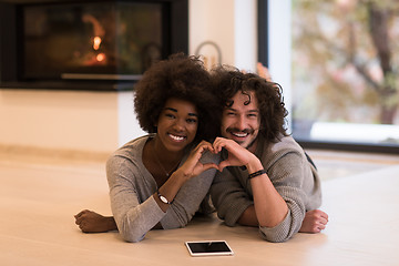 Image showing multiethnic couple used tablet computer on the floor