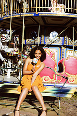 Image showing cool real teenage girl with candy near carousels at amusement pa