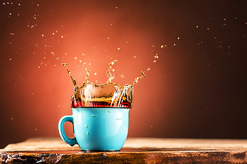 Image showing Brown splashes out drink from cup of tea on a brown background